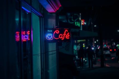 Illuminated sign with cafe text in city at night