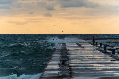 Pier over sea against sky during sunset