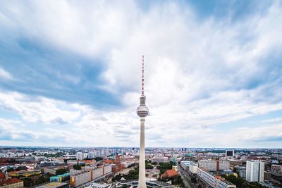 High section of fernsehturm amidst town against cloudy sky