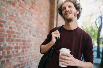 Portrait of smiling young man with coffee in the wall