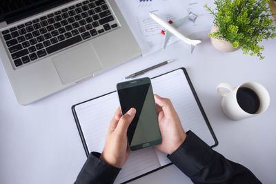 High angle view of hand using mobile phone on table