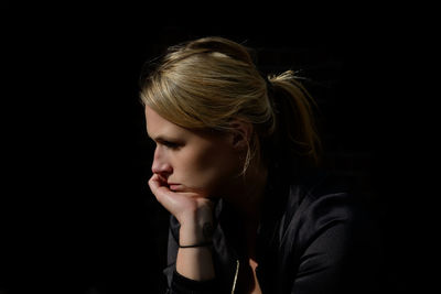 Young woman looking away over black background