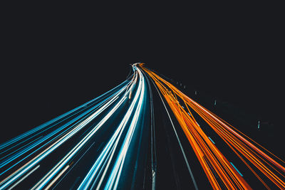 Light trails on bridge against clear sky at night