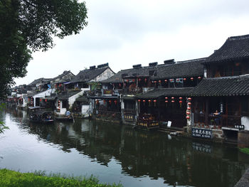 Buildings by lake against sky in city