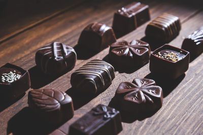 Pralines on wooden base, deep shadows, close up. sweet and chocolate concept.