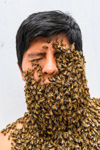 Man's face covered by bees