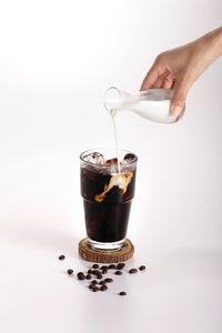 Midsection of person pouring coffee in cup against white background