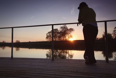 Silhouette man standing by tree against sky during sunset