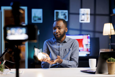 Portrait of young man using mobile phone at table