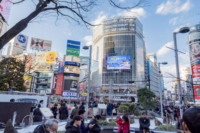 People on city street by buildings against sky