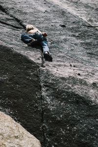 Low angle view of man rock climbing on sunny day