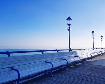 Street light by sea against clear blue sky