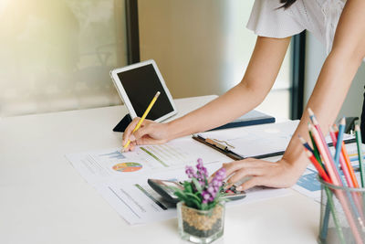 Midsection of woman using mobile phone on table