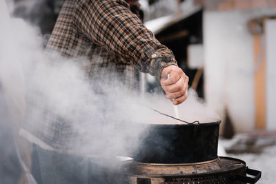 Midsection of man working on barbecue grill