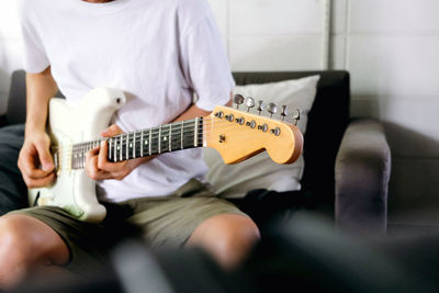 Midsection of man playing guitar