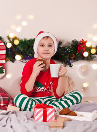 Portrait of cute girl playing with christmas tree at home