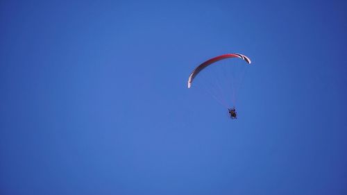 Low angle view of person paragliding against clear blue sky