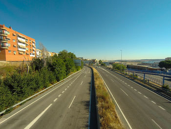 Road passing through city against clear sky