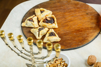 Gomentashi cookies for purim holiday on a table on a wooden board next to the menorah.