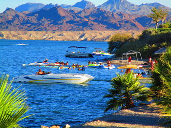 Boats in sea against mountains