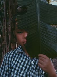 Portrait of boy looking away while standing by tree