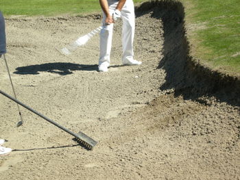 Low section of man standing on sand