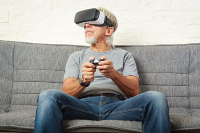 Man holding camera while sitting on sofa