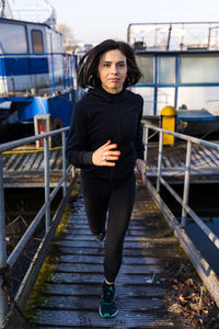 Young adult woman is running on a ship gangway in the morning - concept of health and wellness