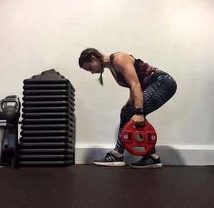 Man holding camera while standing against wall