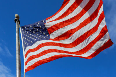 Low angle view of american flag against blue sky