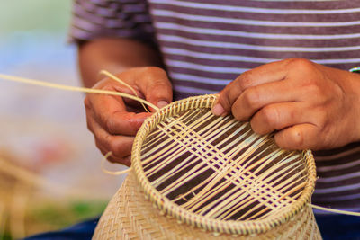 Midsection of man making wicker decoration