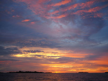 Scenic view of sea against dramatic sky during sunset