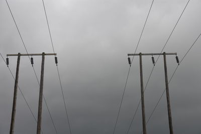 Low angle view of silhouette electricity pylon against sky