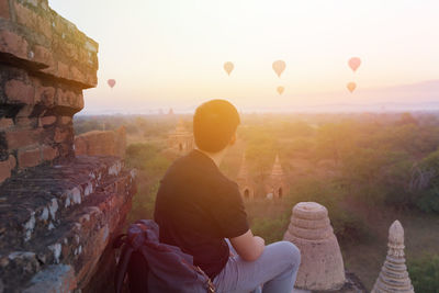 Rear view of man sitting on hot air balloon against sky