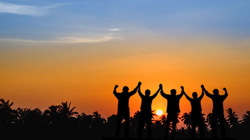 Silhouette people against orange sky