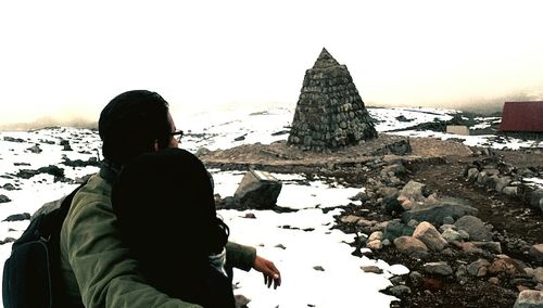 Rear view of people sitting on rock