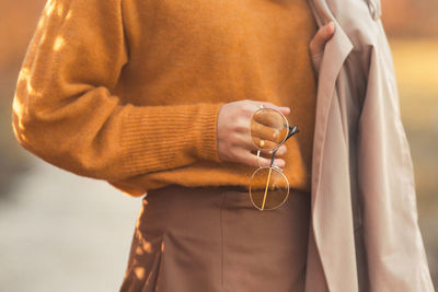 Midsection of woman holding sunglasses