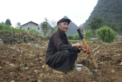 Side view of man holding umbrella against sky