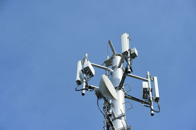 Low angle view of telephone pole against clear blue sky