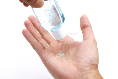 Close-up of hand holding drink against white background