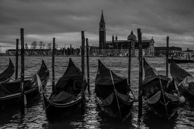 Gondolas moored at port against san giorgio maggiore