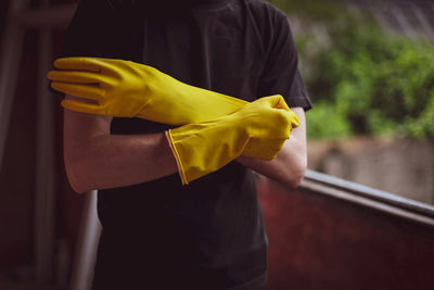 Caucasian male builder wears yellow gloves.