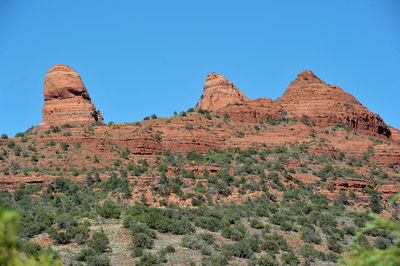 Rock formations on landscape against clear blue sky