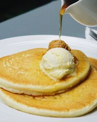 Syrup pouring on pancakes in plate