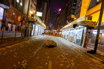 Illuminated street amidst buildings in city at night