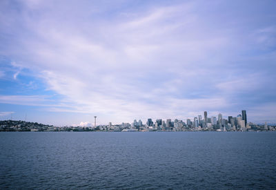 City at waterfront against cloudy sky