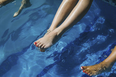 Women's legs dangling in swimming pool