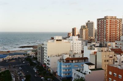 High angle view of buildings by sea against clear sky