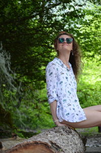 Young woman wearing sunglasses standing by plants in forest