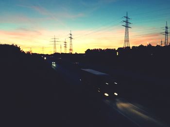 Cars on road against sky during sunset